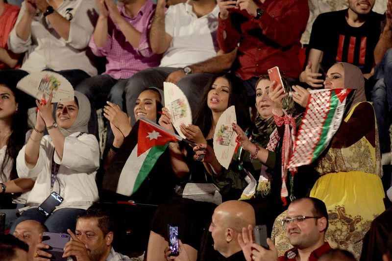 Women celebrating with a Jordanian flag and a red shemagh at the Jerash Festival
