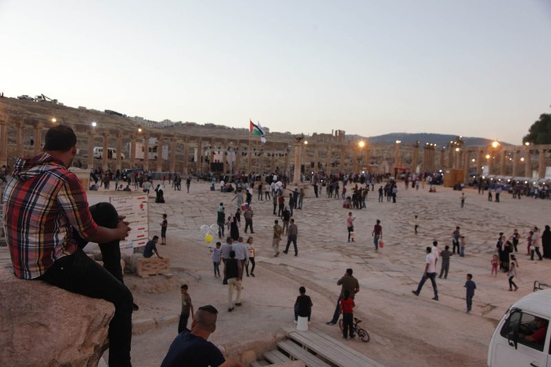 Families and friends gathering in the Oval Plaza of Jerash on a summer evening