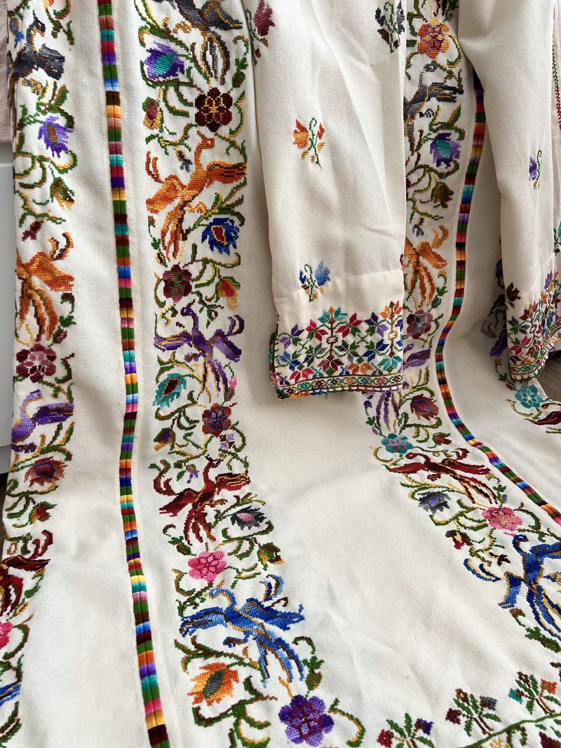 A white traditional thobe covered in hand cross-stitched flowers