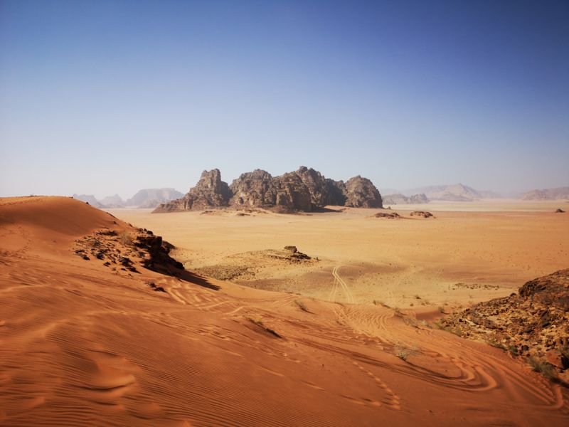 Red sand dunes in Wadi Rum, with rock mountains rising from the desert floor
