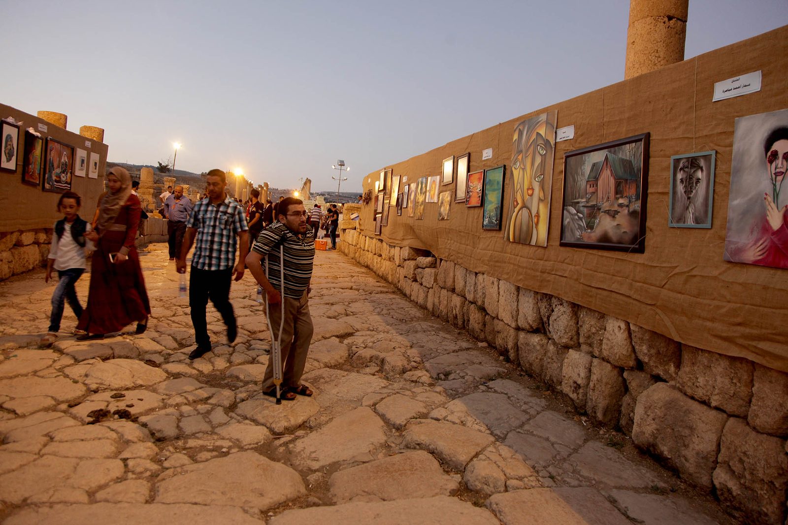 Paintings displayed along an ancient stone wall