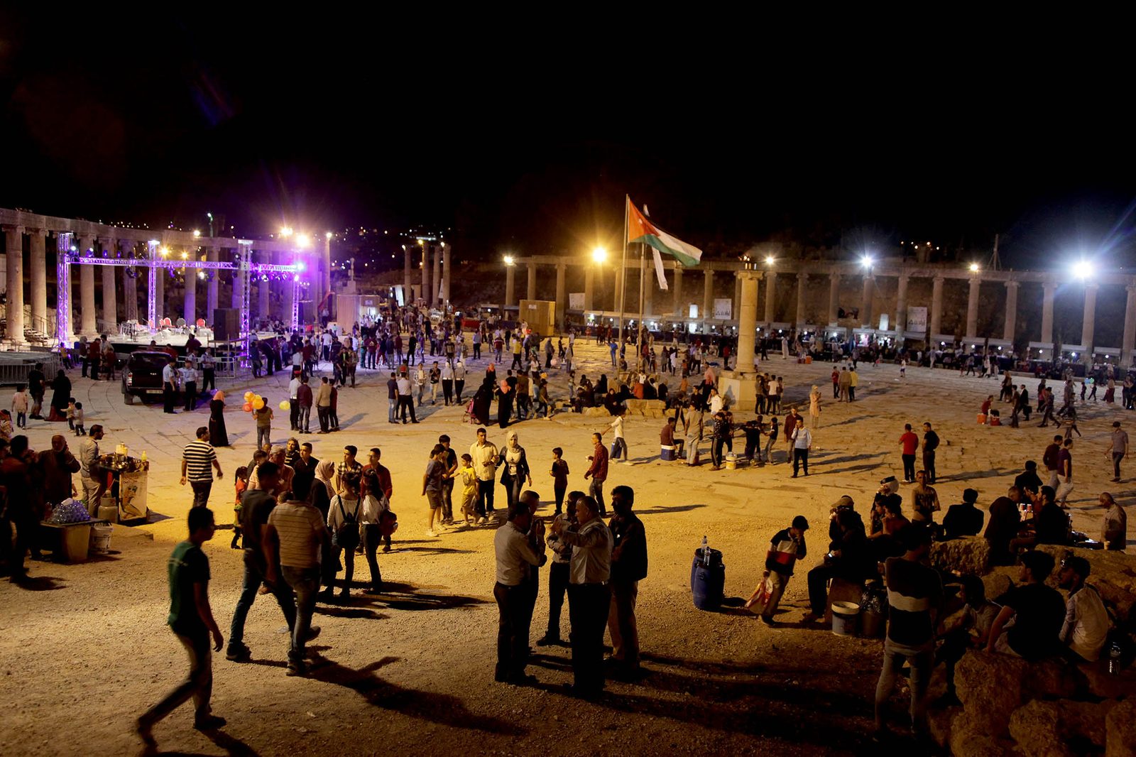Crowds in a lit colonnaded plaza at night